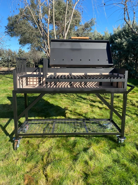Barbacoa argentina modelo CHE de Wagner Grills con tapa de cierre, sistema de elevación frontal y brasero lateral integrado