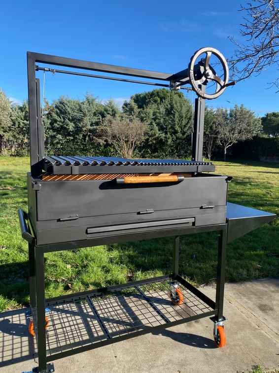 Barbacoa argentina de leña y carbón modelo Velázquez de Wagner Grills, con gran superficie de asado y sistema de manivela profesional