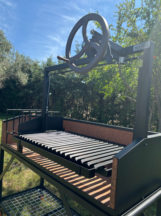 Primer plano de la parrilla argentina Tobi con rejilla de acero y área de quemado lateral para producción constante de brasa.
