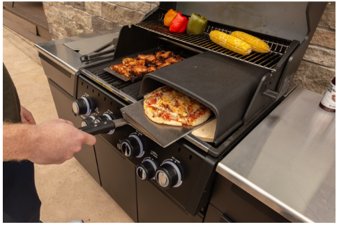 Barbacoa Broil King Baron 490 IR BI en funcionamiento con accesorio de horno para pizza sobre las parrillas