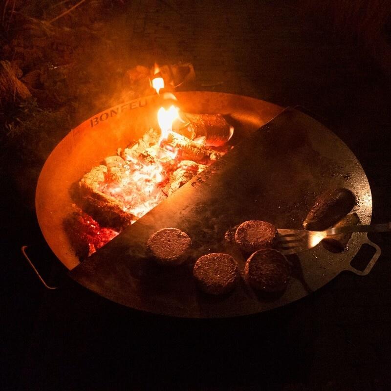 Barbacoa nocturna cocinando hamburguesas sobre la plancha del brasero BonBowl Plus.