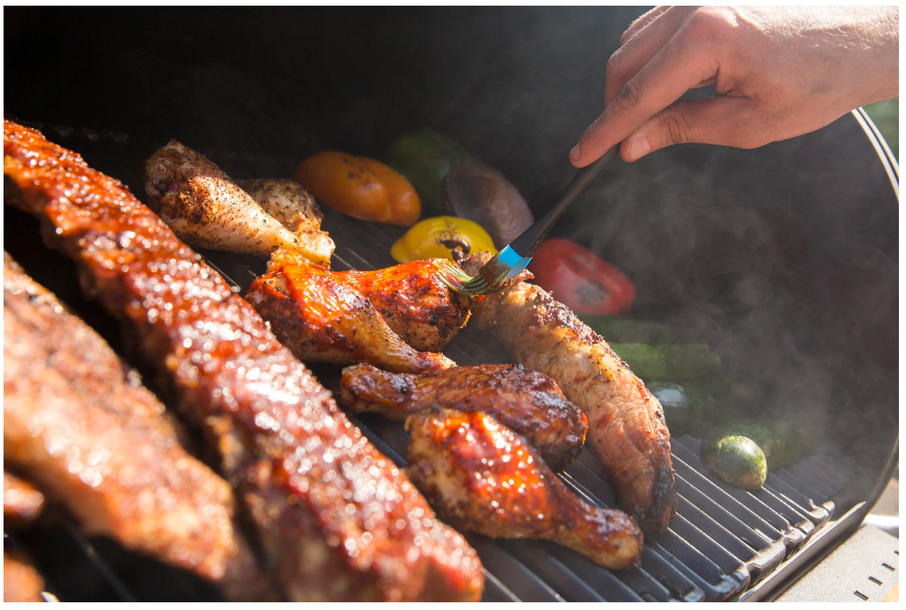 Costillas de cerdo y verduras ahumándose lentamente en la barbacoa Broil King Regal Offset 500