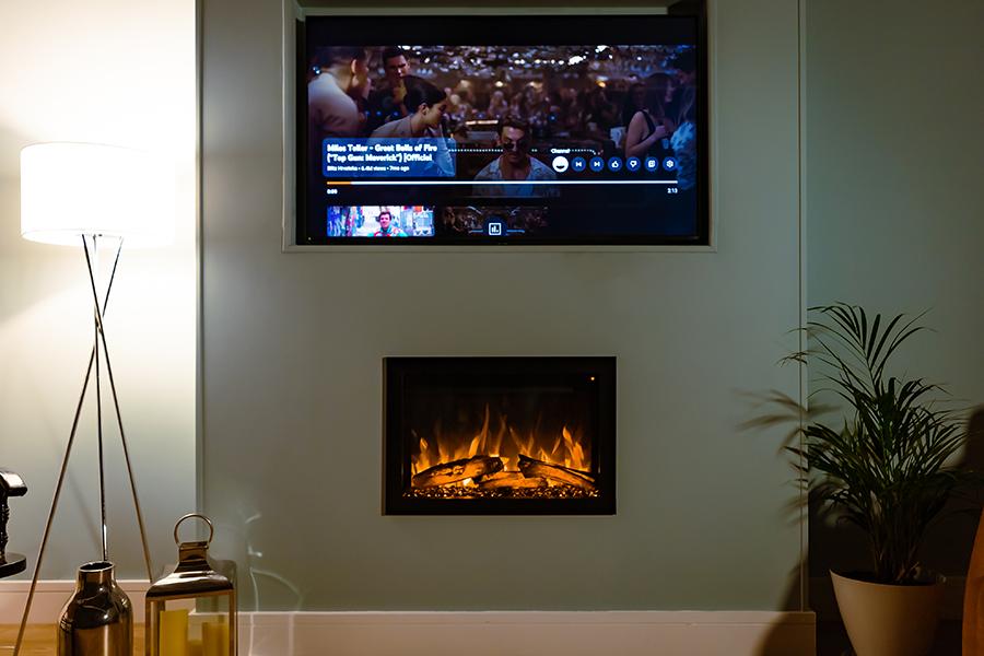 Chimenea Elcofire Motion instalada bajo televisor en salón luminoso con luz ambiental