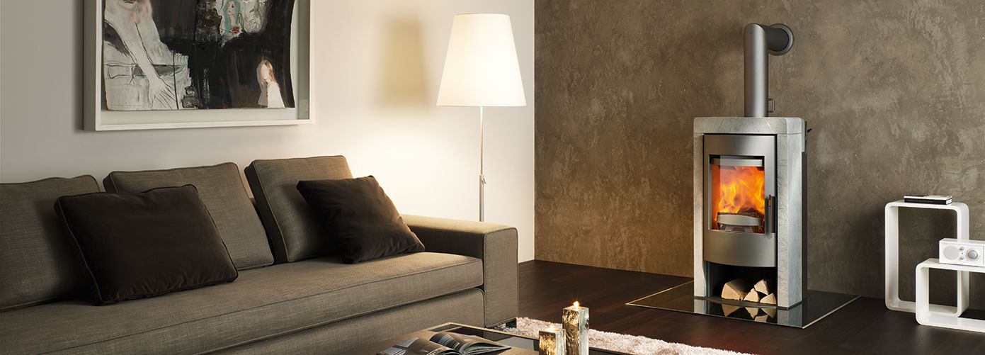 Estufa de leña Rika Fox instalada en un salón moderno con decoración en tonos grises y madera.
