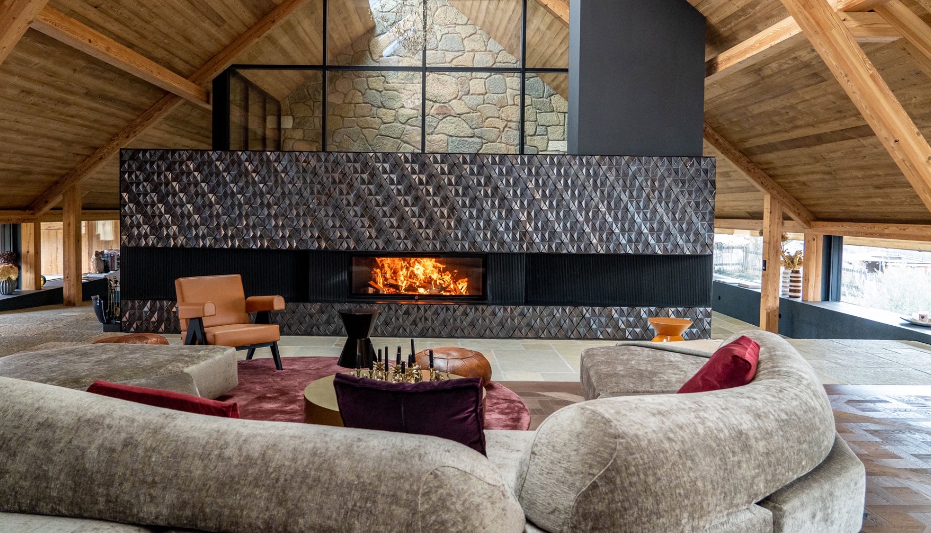 Chimenea de leña panorámica Hoxter Haka 110/51h integrada en una estructura de salón de diseño con techos altos y vigas de madera