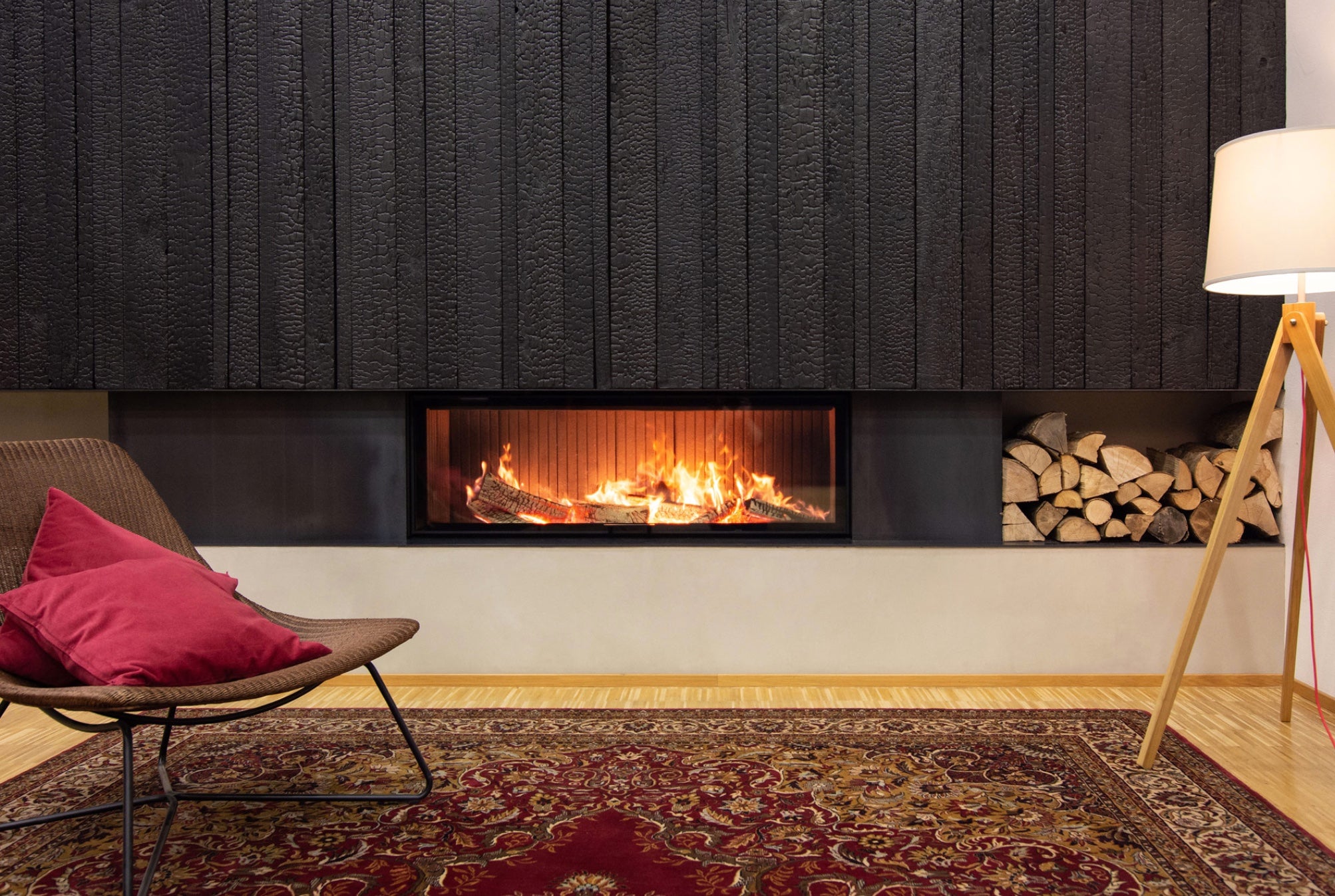 Chimenea panorámica de gran formato Hoxter Haka 150/51h integrada en un salón moderno con diseño minimalista y zona de almacenaje de leña.