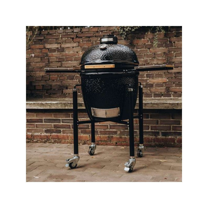 Kamado Monolith ONE.55 ubicado en un patio rústico, mostrando su diseño robusto y acabado negro brillante