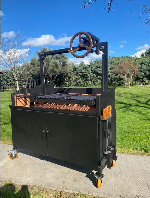 Parrilla argentina Tobi Premium con acabado negro forjado, ruedas industriales con freno y brasero lateral para un asado tradicional